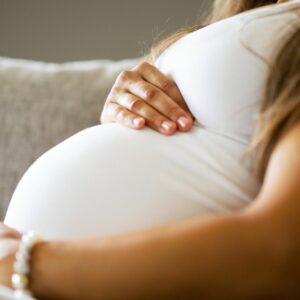 Imagen de una mujer embarazada sentada en un sofá sosteniendo su barriga